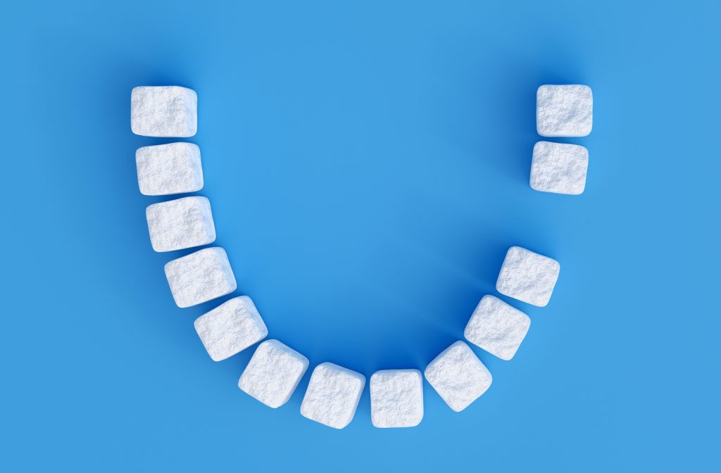 A smile made out of sugar cubes with one missing to represent a missing tooth.